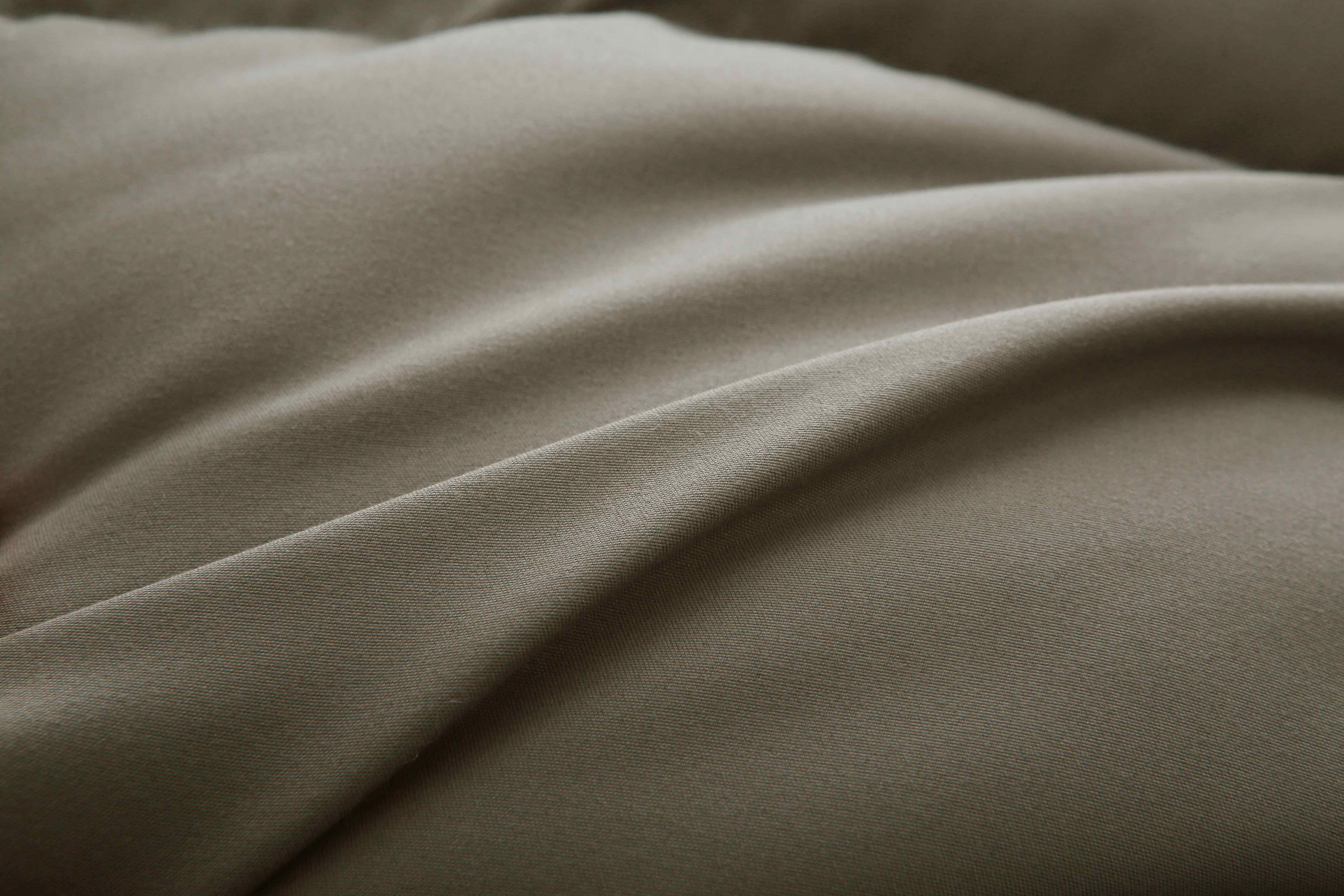 Close-up van het taupe 4-seizoenen dekbed van Zorgmatras, met zichtbare naden en vulling