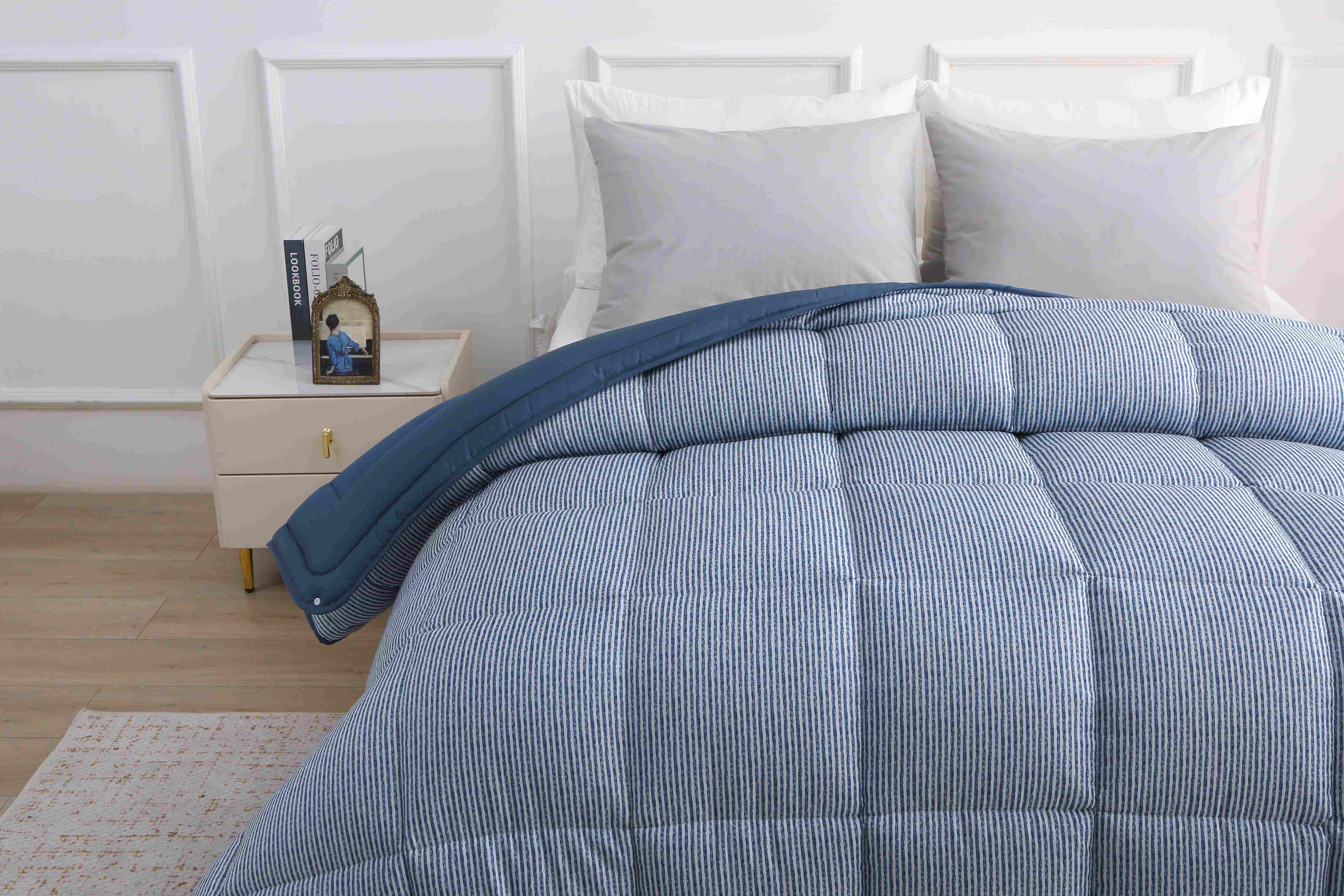 Modern opgemaakt bed met het 2-delige blauwe 4-seizoenen dekbed met vaste hoes in een lichte slaapkamer.
